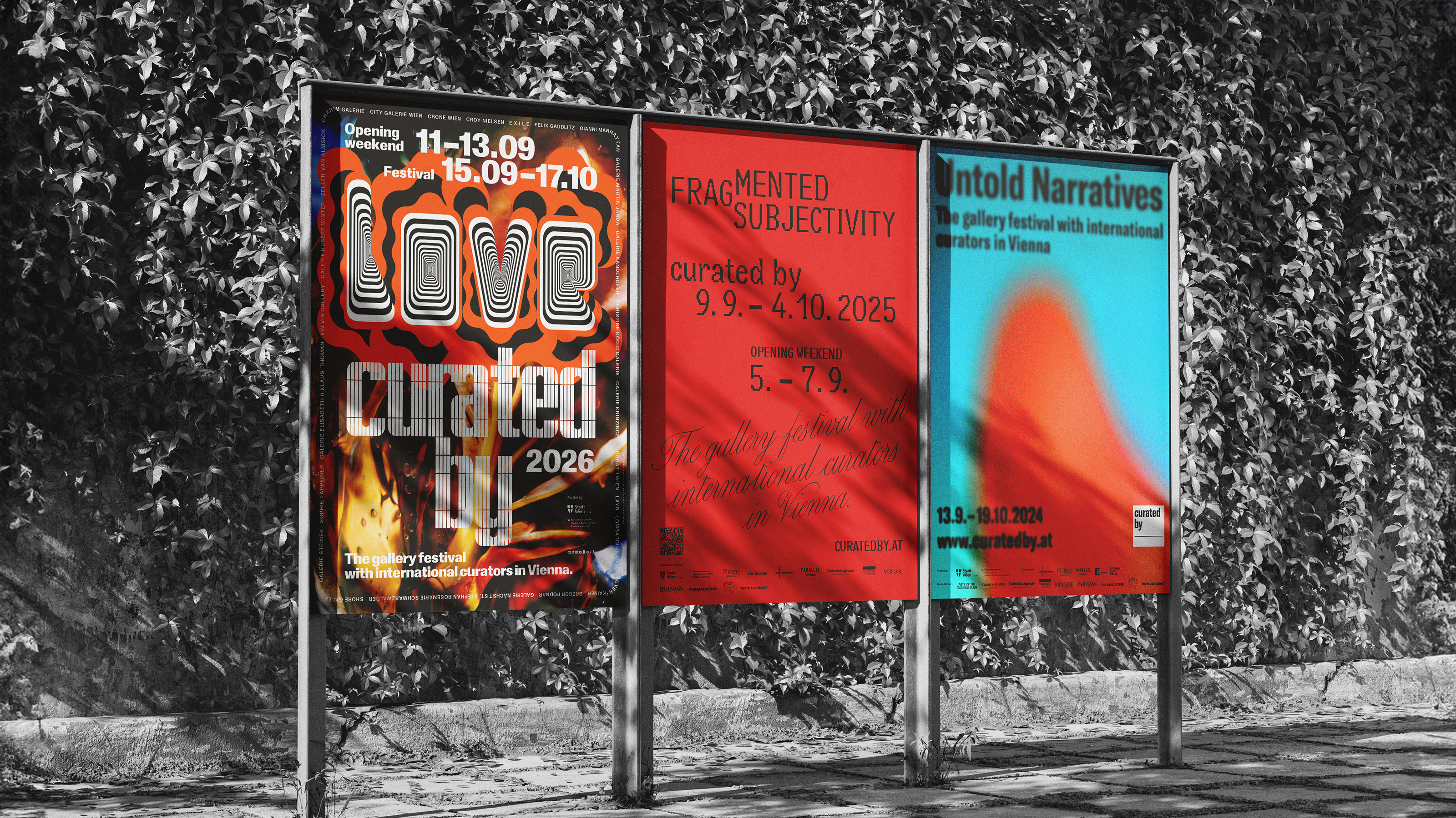 Black and white photo of a billboard in front of an ivy covered wall showing three colour posters for curated by. On the left is the 2026 poster with the title “LOVE” in black and white op art letters on orange cloud shapes. In the middle is the red 2025 poster “Fragmented Subjectivity”. On the right is the turquoise and orange 2024 poster “Untold Narratives”.